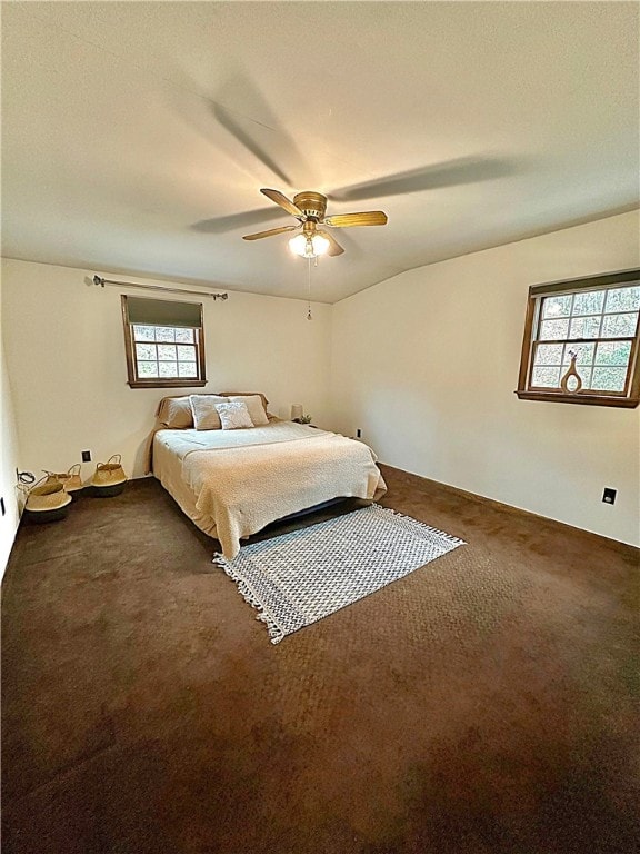 bedroom featuring ceiling fan, dark carpet, and multiple windows