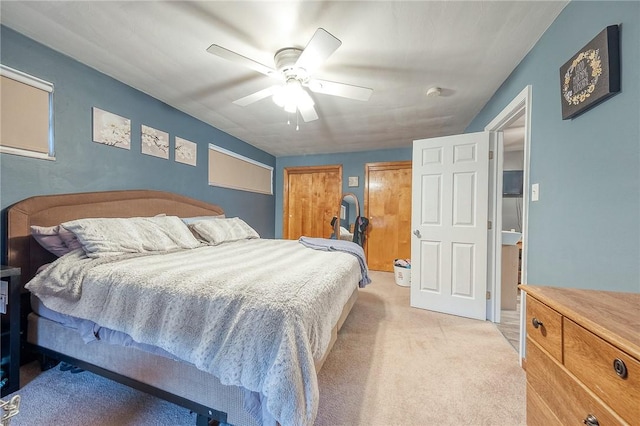 carpeted bedroom with ceiling fan and multiple closets