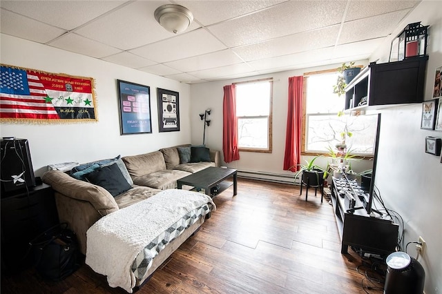 living room with a paneled ceiling, baseboard heating, and dark wood-type flooring