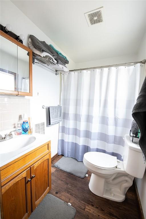 bathroom with hardwood / wood-style floors, vanity, toilet, and tasteful backsplash