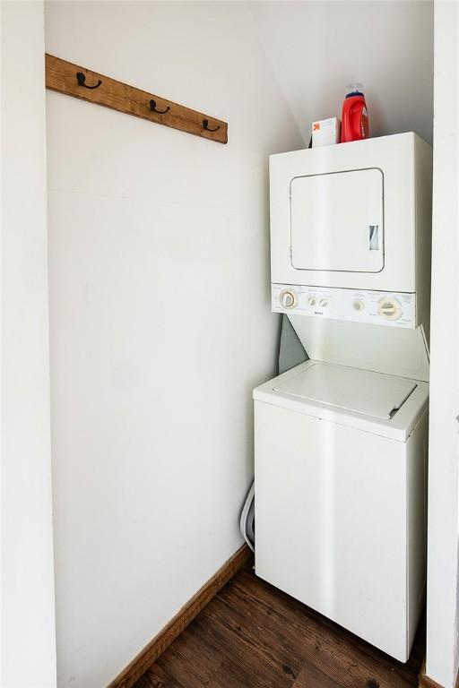 laundry room with dark hardwood / wood-style flooring and stacked washer and dryer