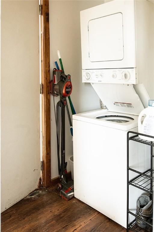 laundry room featuring dark wood-type flooring and stacked washing maching and dryer