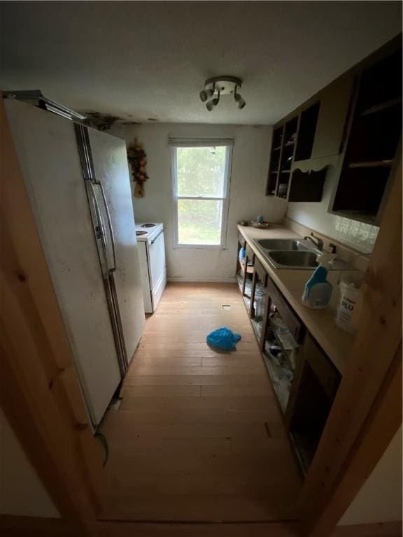 kitchen featuring dishwashing machine, sink, white fridge, and light wood-type flooring