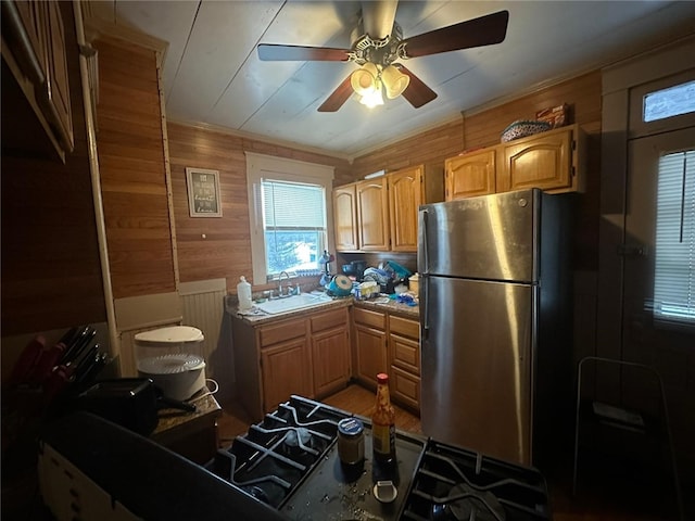 kitchen with stainless steel appliances, ceiling fan, wooden walls, and sink