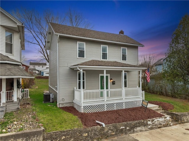 view of front of property featuring a lawn, cooling unit, and a porch