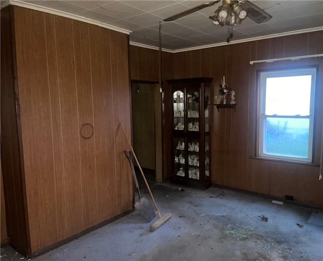 unfurnished room with wood walls, ceiling fan, and ornamental molding