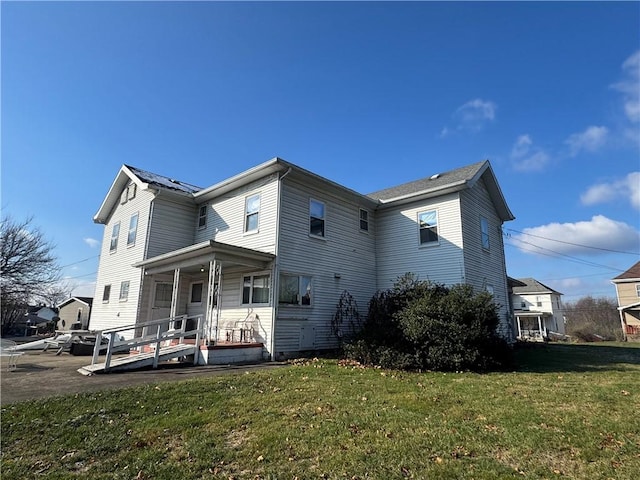 rear view of house with a porch and a yard