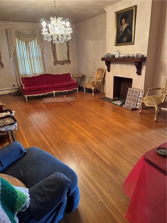 living room featuring hardwood / wood-style floors, a chandelier, a baseboard radiator, and ornamental molding