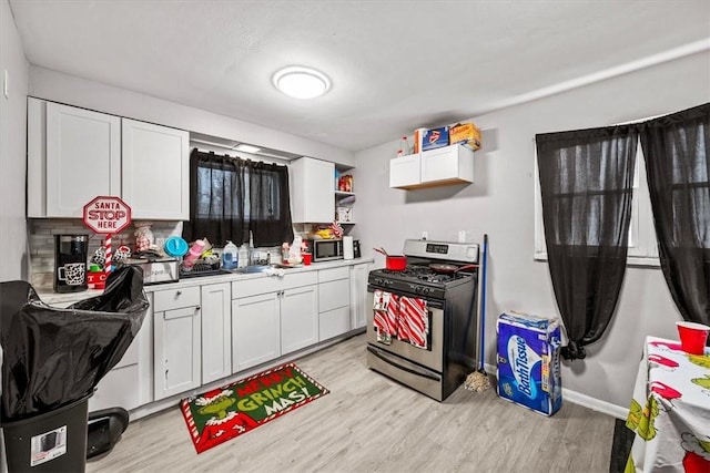 kitchen featuring decorative backsplash, light wood-type flooring, white cabinetry, and appliances with stainless steel finishes