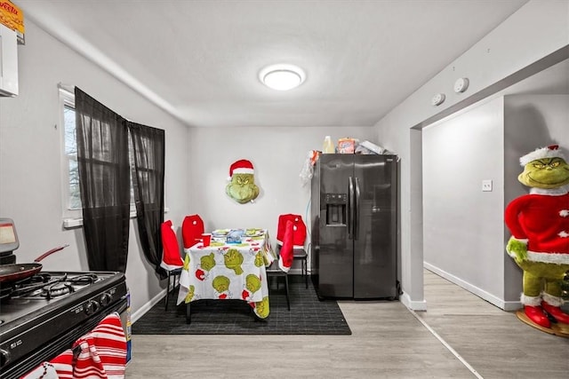 kitchen with gas stove, stainless steel fridge with ice dispenser, and light hardwood / wood-style flooring