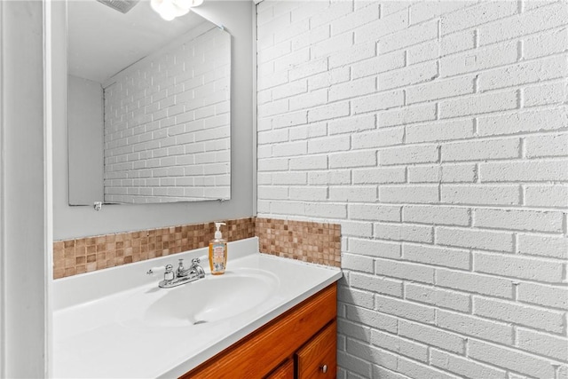 bathroom with vanity and brick wall