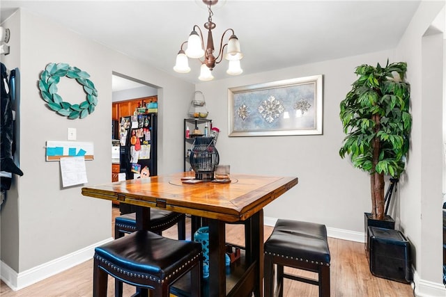 dining space with an inviting chandelier and light hardwood / wood-style flooring