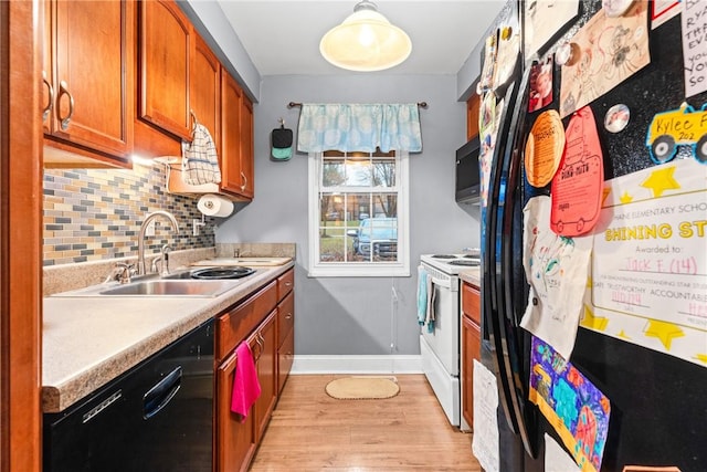 kitchen with backsplash, sink, black appliances, decorative light fixtures, and light hardwood / wood-style floors