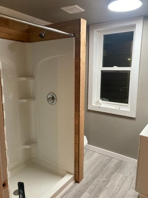 bathroom featuring toilet, a shower, wood-type flooring, and vanity