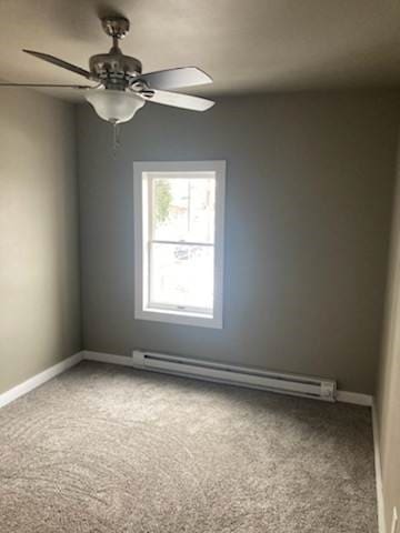 carpeted spare room with baseboard heating and ceiling fan