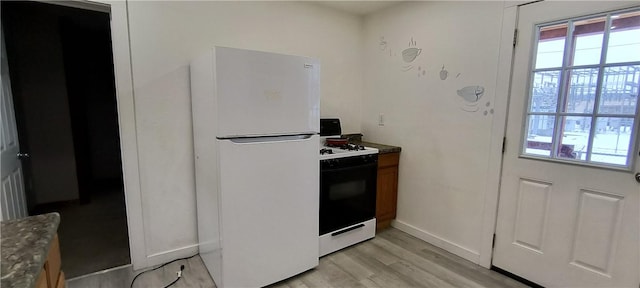 kitchen featuring white refrigerator, range with gas cooktop, and light hardwood / wood-style flooring