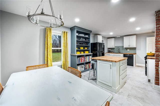 kitchen featuring wood counters, a spacious island, black appliances, decorative light fixtures, and white cabinetry