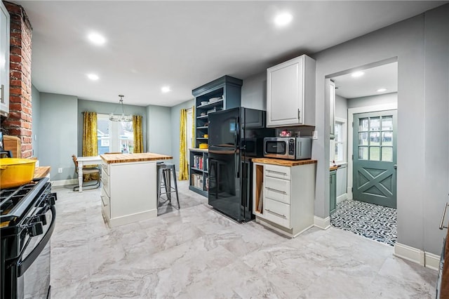 kitchen with butcher block countertops, plenty of natural light, black appliances, and a breakfast bar area