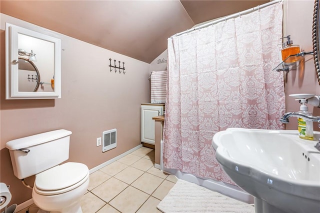 bathroom with toilet, sink, lofted ceiling, and tile patterned flooring