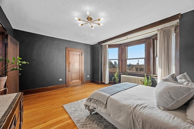 bedroom with a chandelier, radiator heating unit, and light wood-type flooring