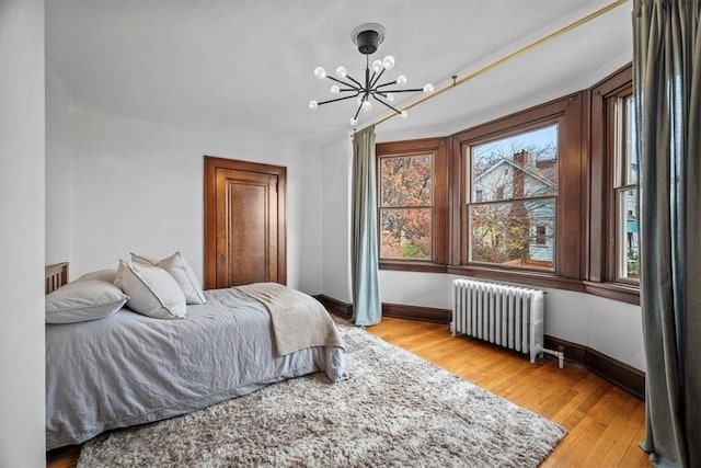 bedroom with a notable chandelier, light hardwood / wood-style floors, and radiator