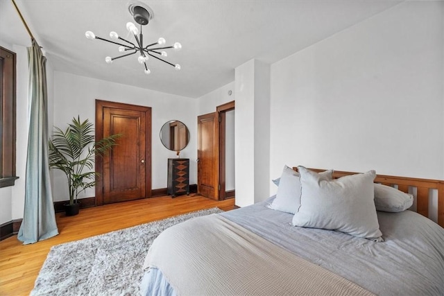 bedroom with an inviting chandelier and light hardwood / wood-style flooring