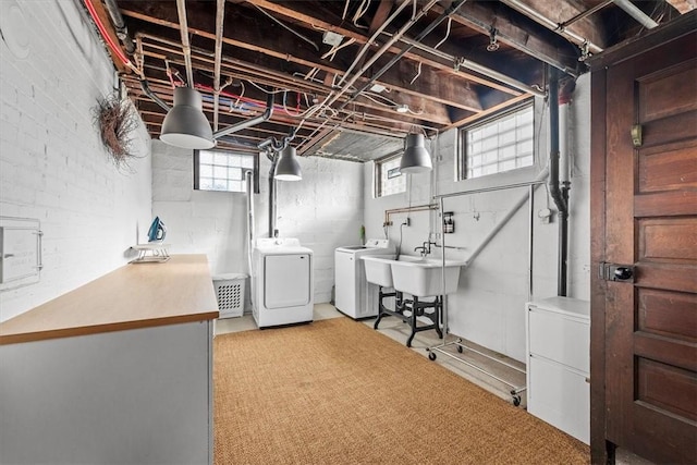 basement featuring brick wall, sink, and washing machine and clothes dryer