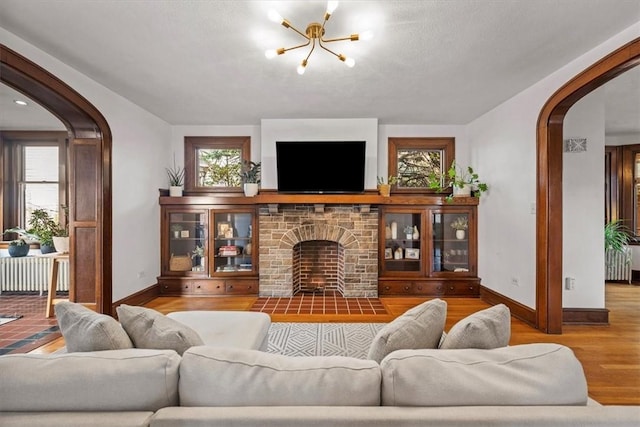 living room featuring plenty of natural light, radiator heating unit, a fireplace, and light hardwood / wood-style flooring