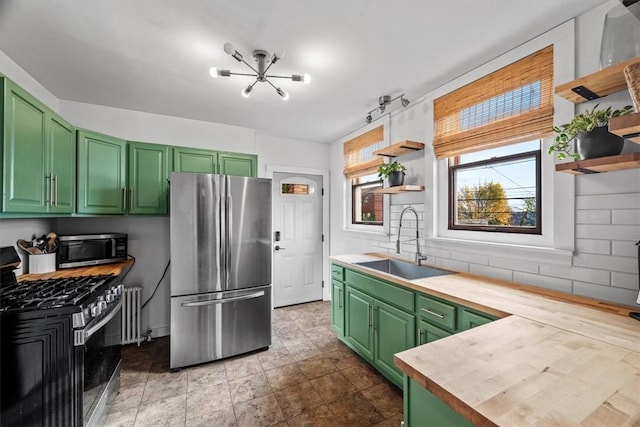 kitchen featuring decorative backsplash, appliances with stainless steel finishes, sink, green cabinetry, and butcher block countertops