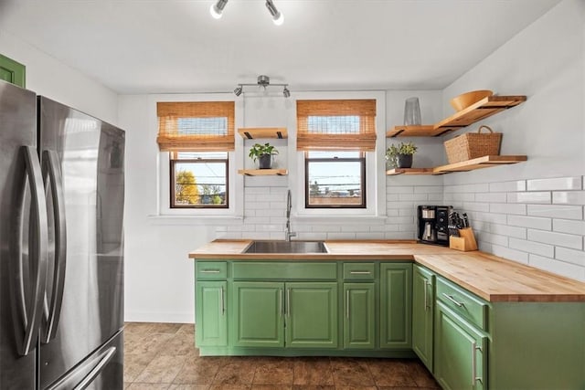 kitchen featuring butcher block countertops, stainless steel fridge, green cabinets, and sink