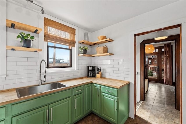 kitchen featuring backsplash, dark tile patterned flooring, sink, green cabinetry, and butcher block countertops