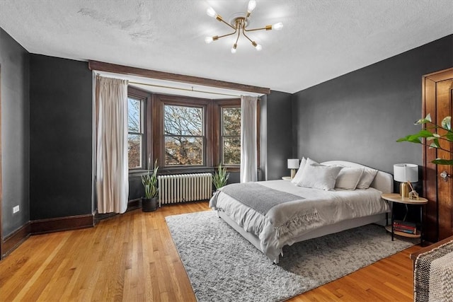 bedroom with a notable chandelier, a textured ceiling, radiator, and light hardwood / wood-style flooring