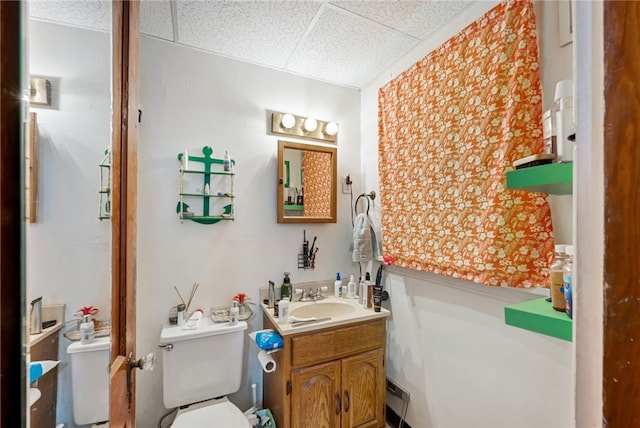 bathroom with a paneled ceiling, vanity, and toilet