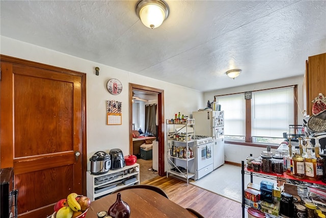 kitchen with a textured ceiling, light hardwood / wood-style flooring, and white appliances