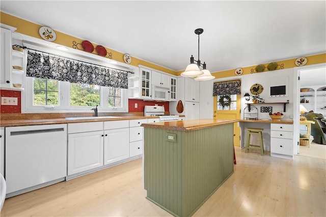 kitchen with sink, white cabinetry, a center island, hanging light fixtures, and white appliances