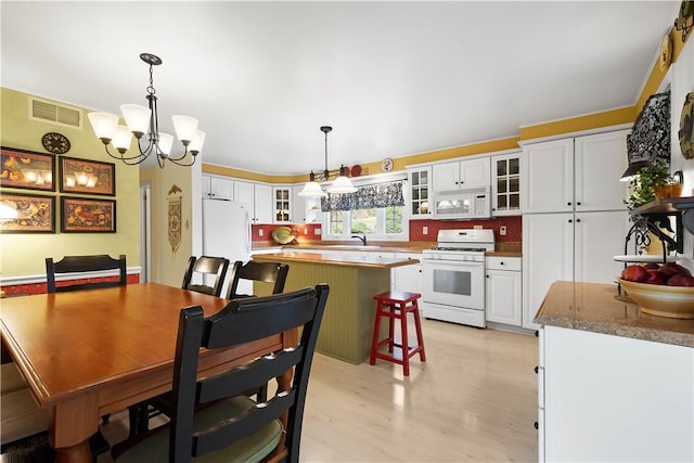 dining space featuring sink, a chandelier, and light wood-type flooring