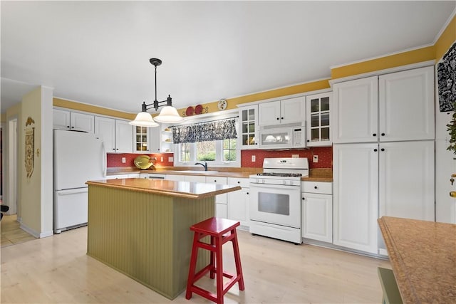 kitchen featuring sink, white appliances, a center island, white cabinets, and decorative light fixtures