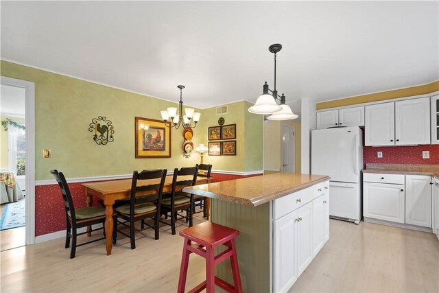 kitchen featuring a center island, white fridge, light hardwood / wood-style floors, and white cabinetry