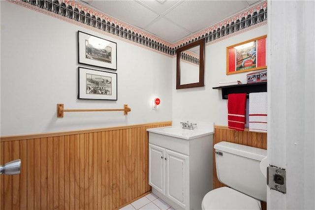 bathroom with vanity, tile patterned flooring, toilet, and wood walls