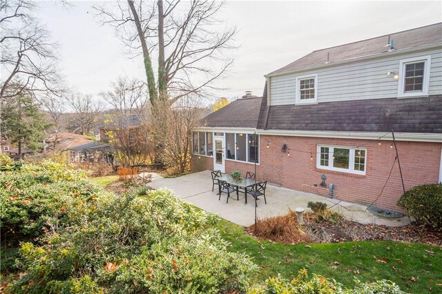 back of property with a lawn, a sunroom, and a patio