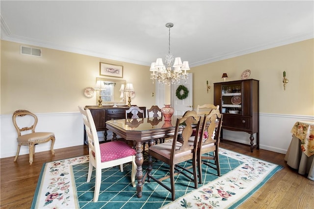 dining space featuring hardwood / wood-style floors, an inviting chandelier, and ornamental molding