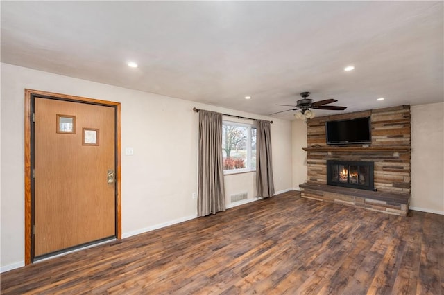 unfurnished living room with a stone fireplace, ceiling fan, and dark wood-type flooring