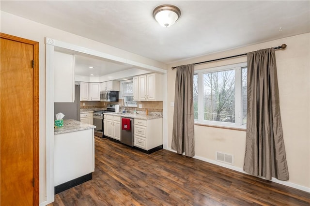 kitchen with light stone countertops, stainless steel appliances, sink, white cabinets, and dark hardwood / wood-style floors