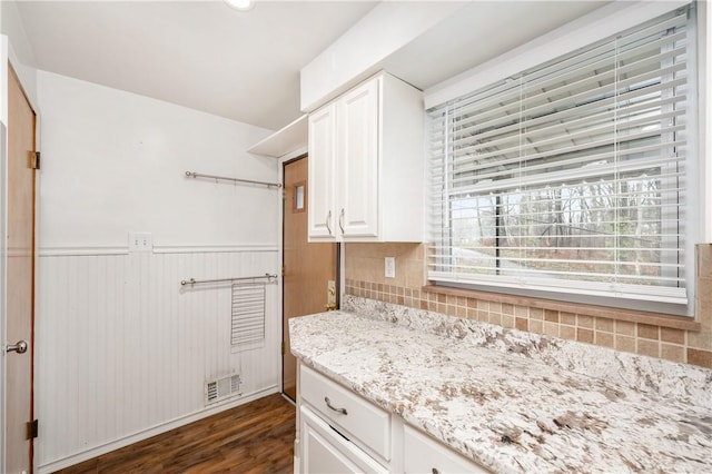 kitchen with tasteful backsplash, light stone countertops, dark hardwood / wood-style flooring, and white cabinets