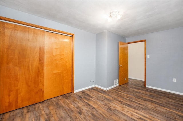 unfurnished bedroom with a closet and dark wood-type flooring