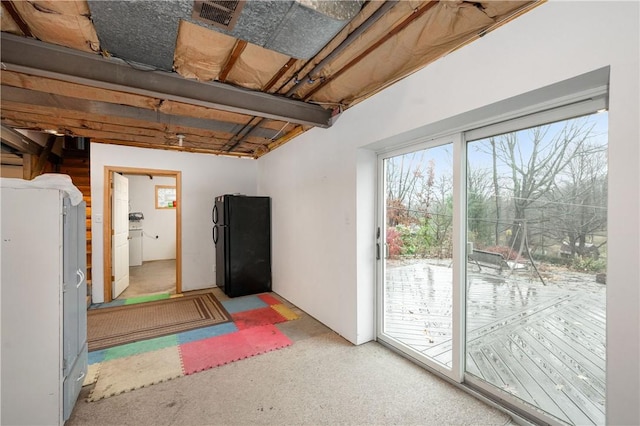 basement featuring carpet, black refrigerator, and white refrigerator