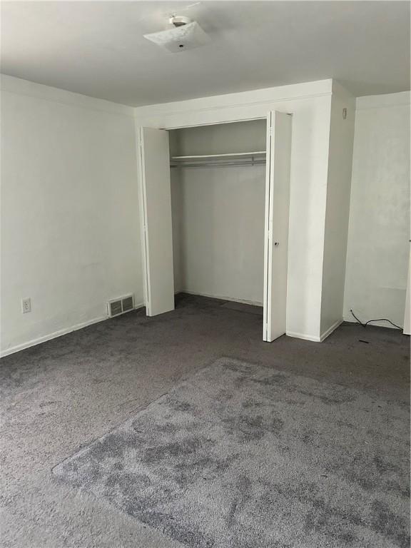 unfurnished bedroom featuring dark carpet and a closet