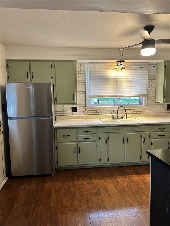 kitchen featuring stainless steel fridge, sink, and green cabinetry