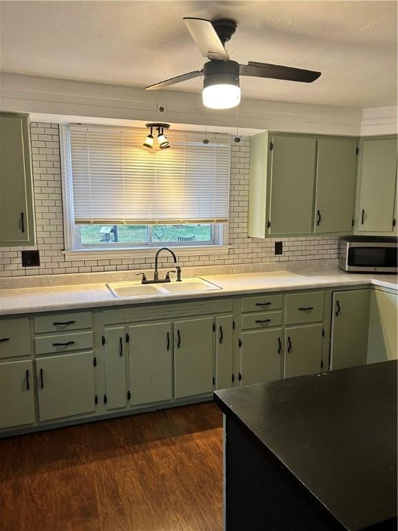 kitchen with decorative backsplash, dark hardwood / wood-style floors, green cabinetry, and sink