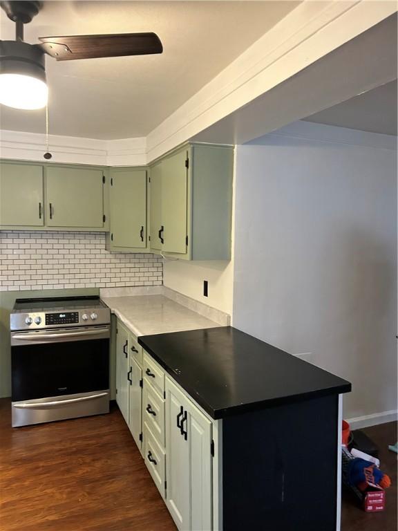 kitchen featuring ceiling fan, dark hardwood / wood-style flooring, backsplash, stainless steel stove, and green cabinetry